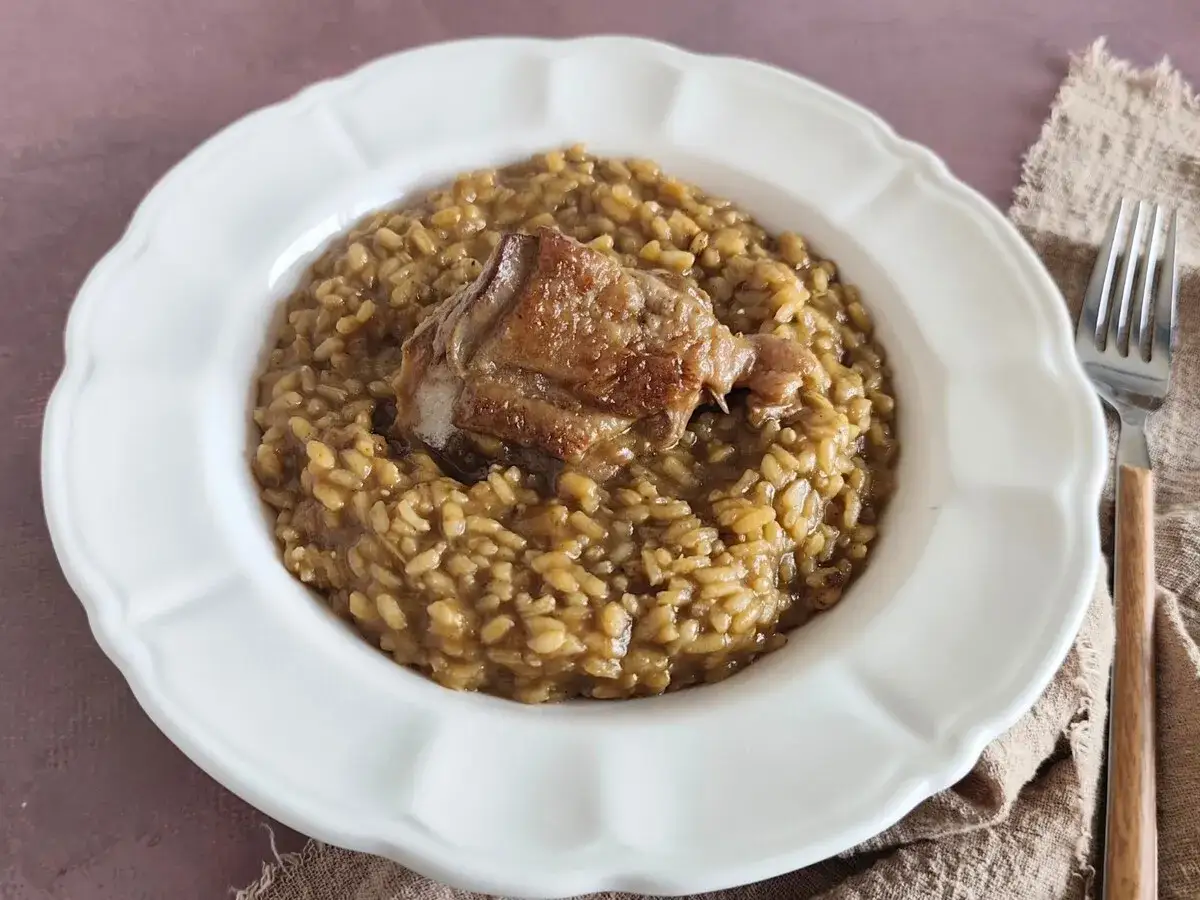 Un plato de arroz caldoso con un trozo de carne dorada encima, como un pitu de caleya casero.