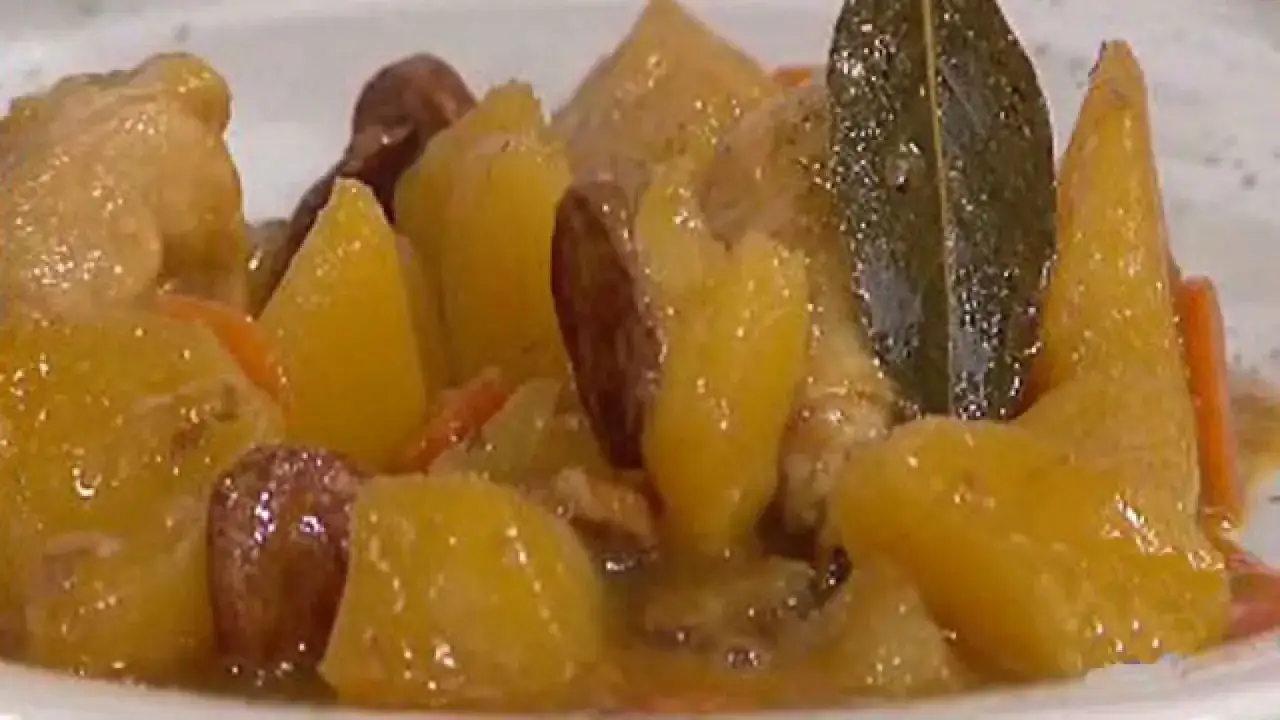 Guiso de pollo con patatas de la abuela, tierno y sabroso, con trozos de zanahoria y una hoja de laurel.
