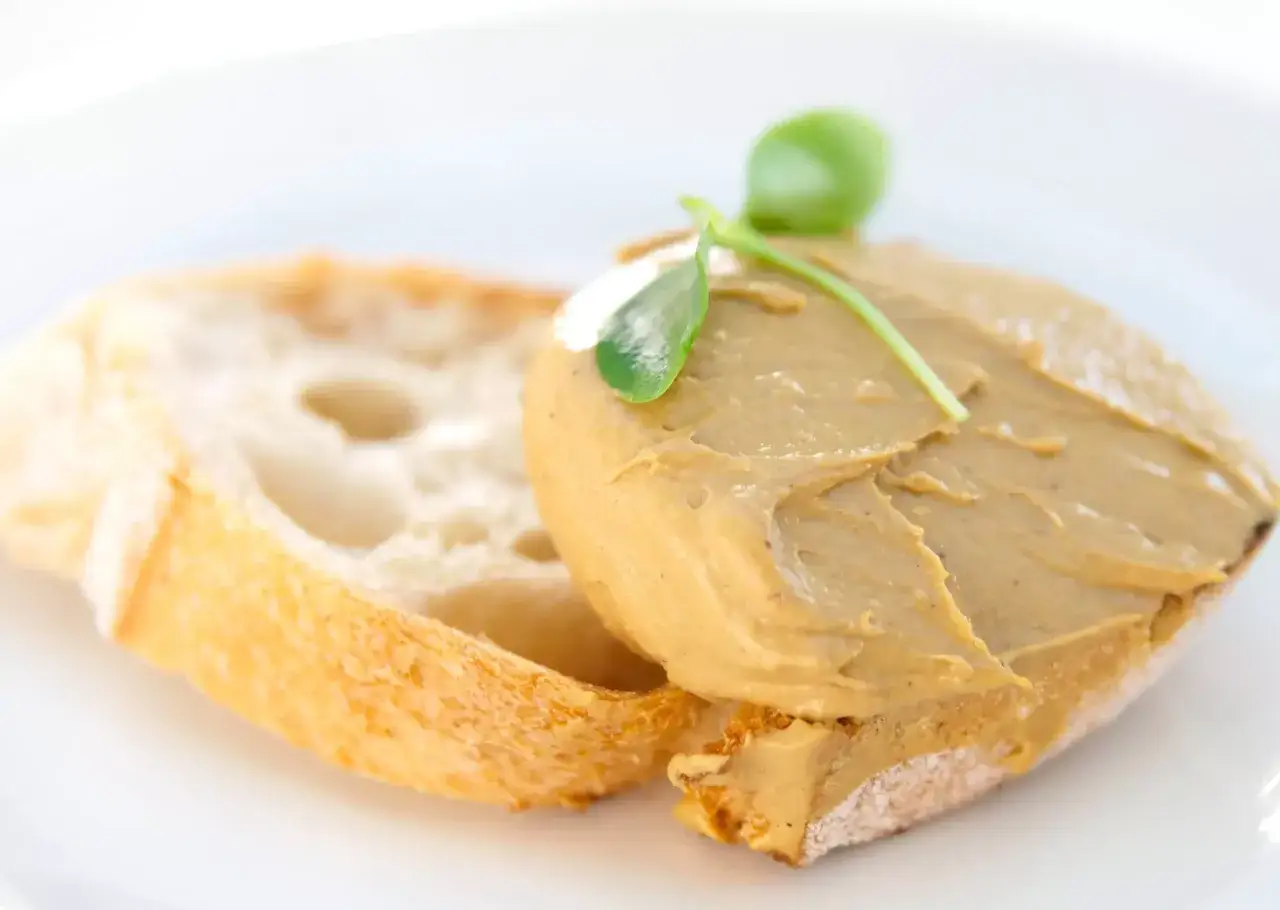 Tostada con pat&eacute; de mejillones y una hoja verde como decoraci&oacute;n.