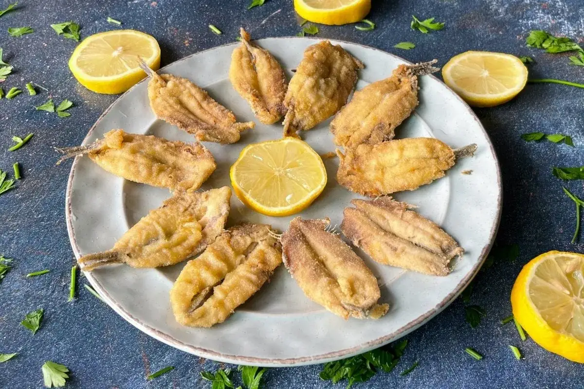 Deliciosos boquerones en freidora de aire, crujientes y dorados, servidos con rodajas de lim&oacute;n y perejil fresco.