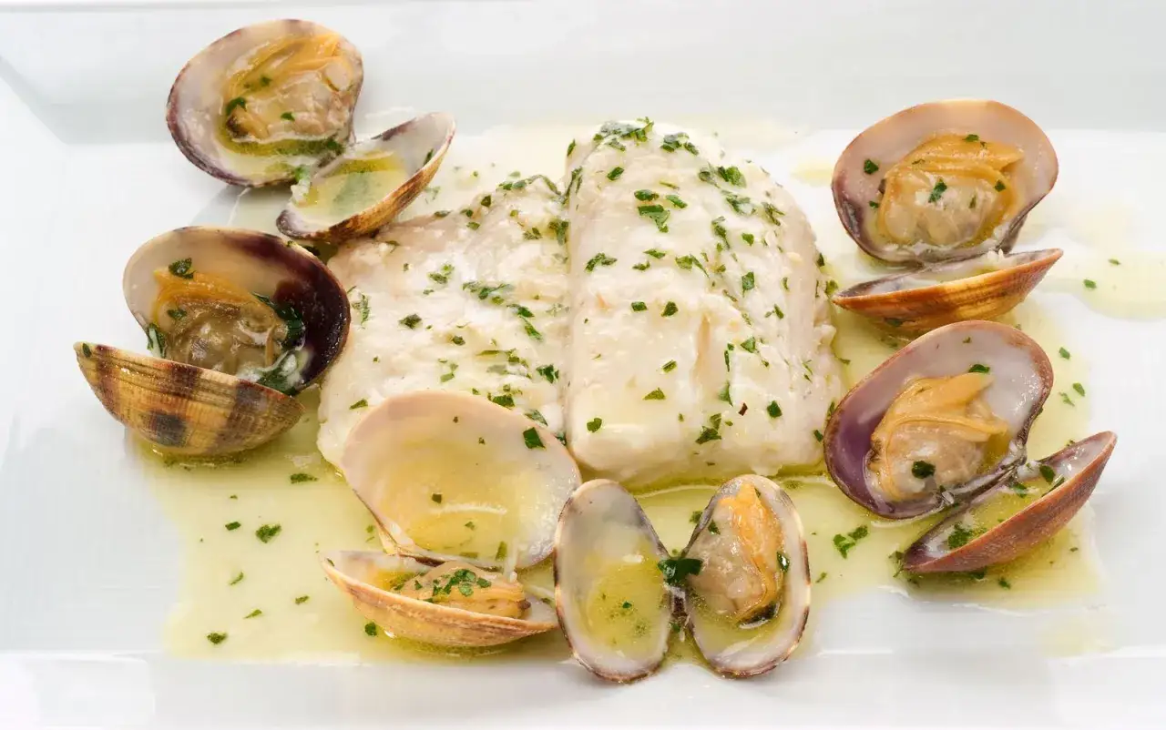 Merluza a la vasca con almejas, un plato delicado con pescado blanco y marisco en salsa.