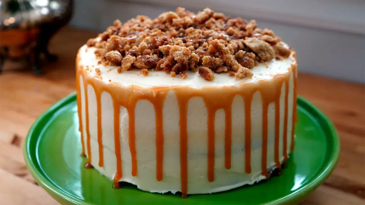 Tarta de caramelo con glaseado blanco y cobertura crujiente. El caramelo chorrea por los lados, invitando a probar esta delicia.