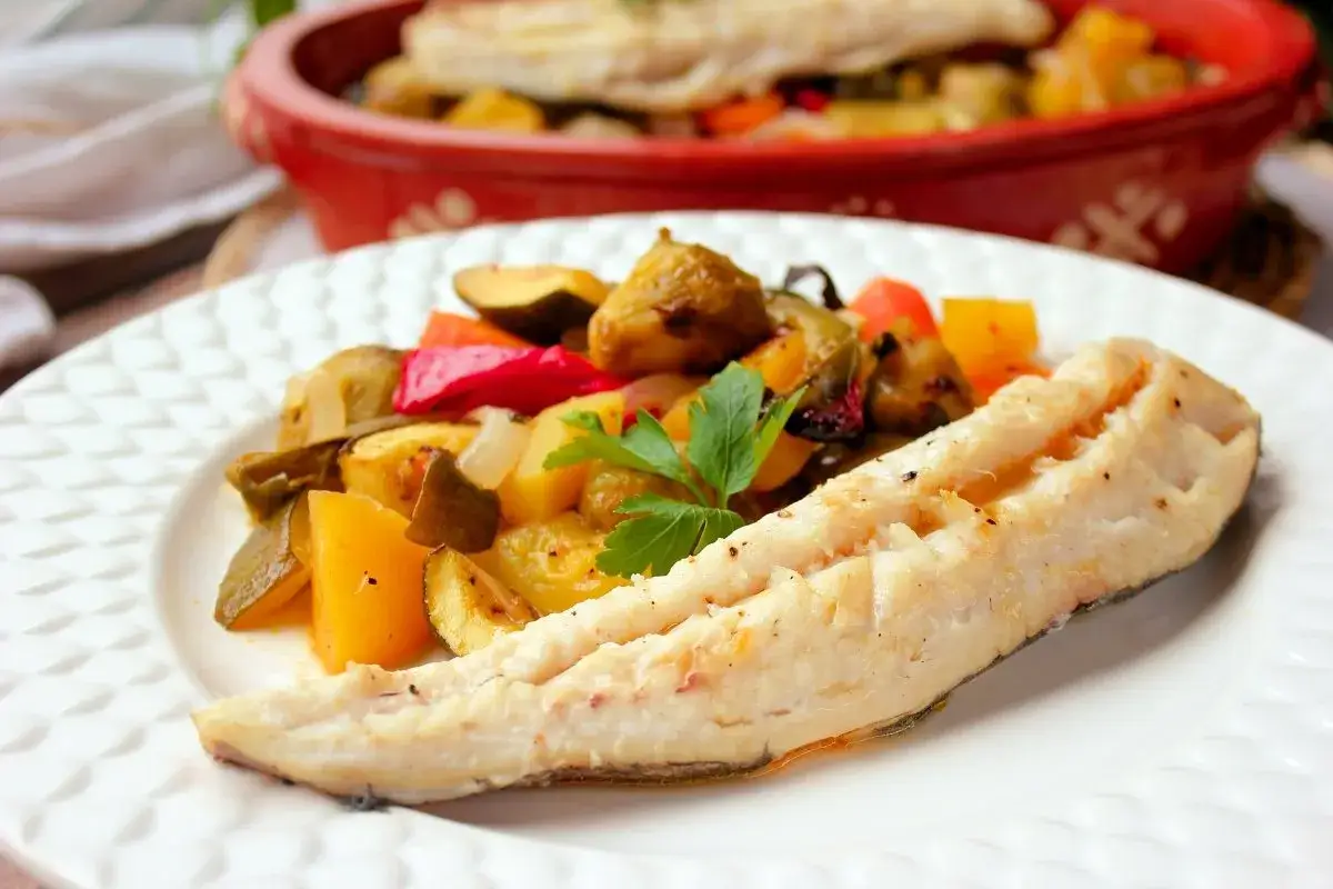 Delicioso merluza al horno con verduras asadas, un plato saludable y lleno de sabor.