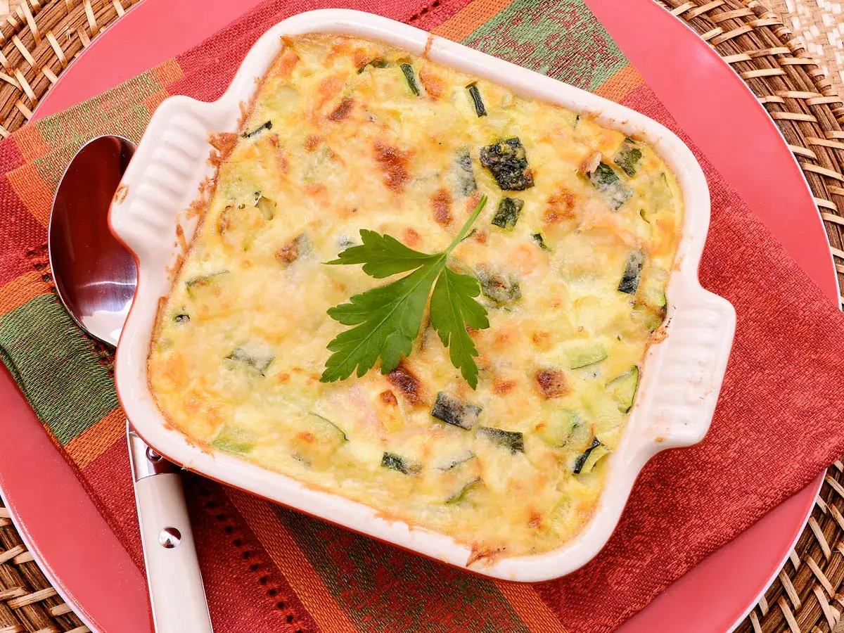 Delicioso pastel de calabacín, jamón y queso recién horneado, adornado con perejil fresco.