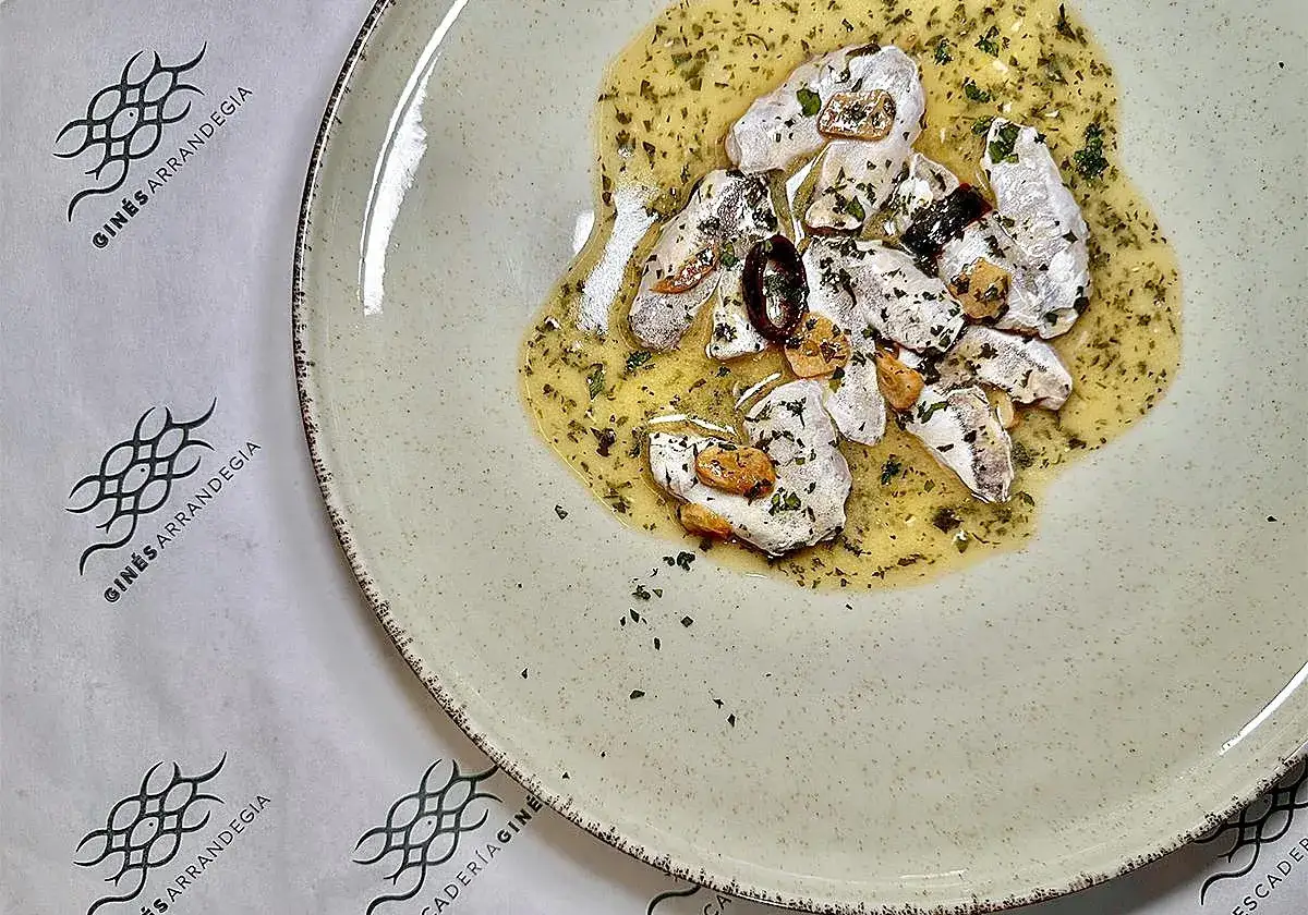 Deliciosas cocochas de merluza en salsa de ajo y perejil, servidas en un plato rústico.