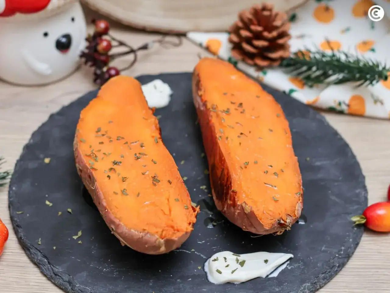 Dos mitades de boniato al horno, espolvoreadas con hierbas, acompa&ntilde;adas de una salsa cremosa.