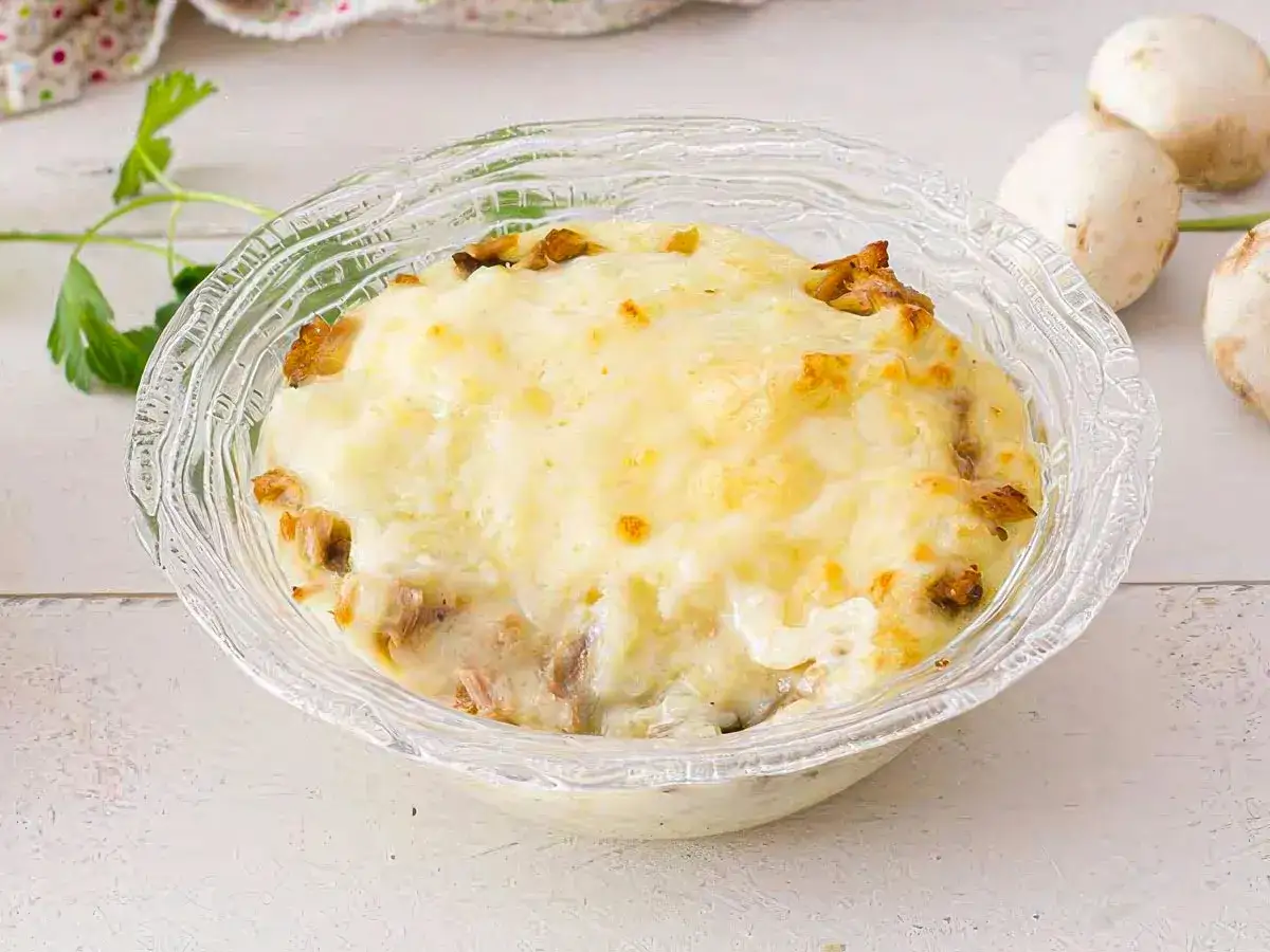 Delicioso pastel de papa gratinado con queso, servido en un cuenco de vidrio.