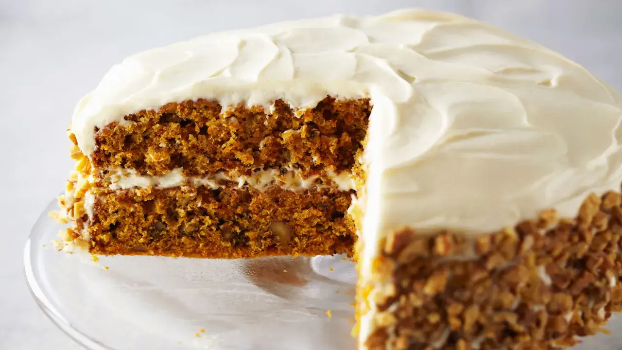 Tarta de zanahoria esponjosa con glaseado cremoso y nueces picadas. ¡Perfecta para tu próxima receta!