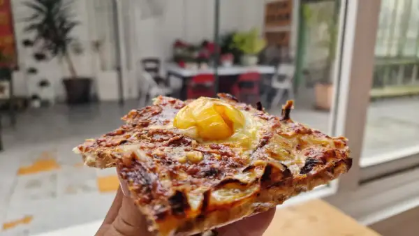 Deliciosa coca de cebolla con huevo frito coronando esta maravilla. Perfecta para un aperitivo o cena rápida.
