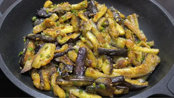 Berenjenas al ajillo salteadas en sartén, con trozos dorados y tiernos, salpicadas de ajo y perejil.