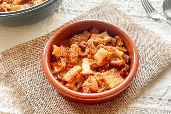 Un cuenco de barro con callos a la vizcaína, un plato tradicional español con trozos de tripa y chorizo en salsa.