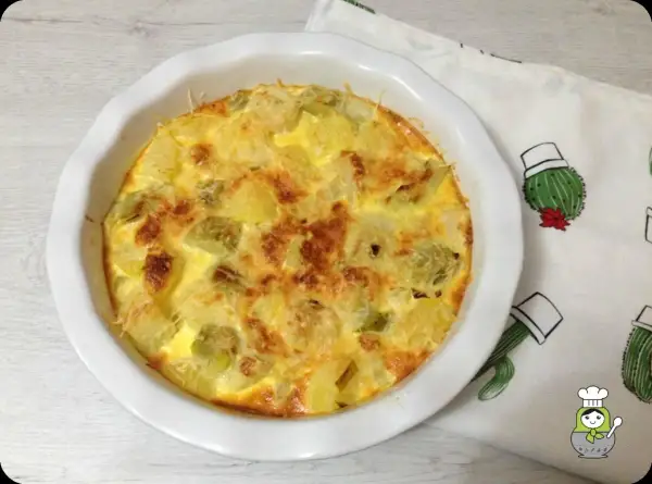Tortilla dorada con trozos de puerros al horno y queso gratinado, lista para disfrutar.