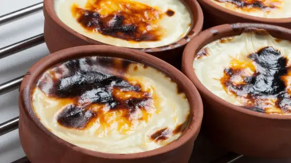 Cuatro cazuelas de barro con tarta de arroz horneada, con una capa superior dorada y caramelizada.