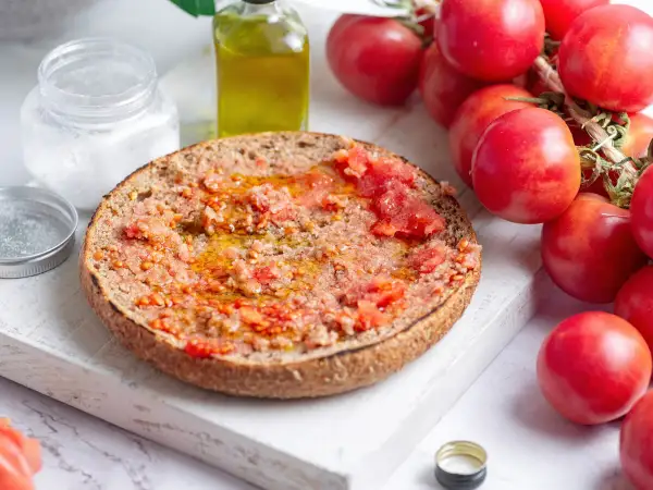 Rebanada de pan tostado con tomate rallado y aceite de oliva, lista para disfrutar de un delicioso pa amb tomàquet.