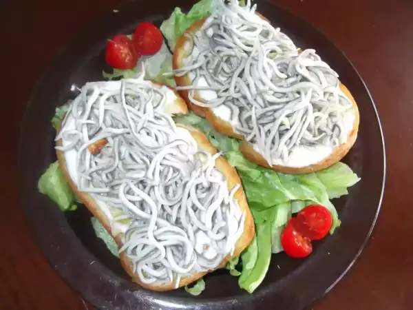Dos tostas de gulas sobre lechuga y tomate cherry, un bocado delicioso.