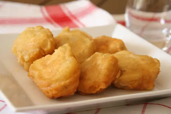 Bocados dorados y crujientes, ¿qué es la pavía pescado? Deliciosos trozos de pescado rebozado en una bandeja blanca.