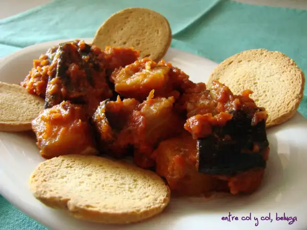 Berenjenas con tomate, un plato casero servido con tostas crujientes.