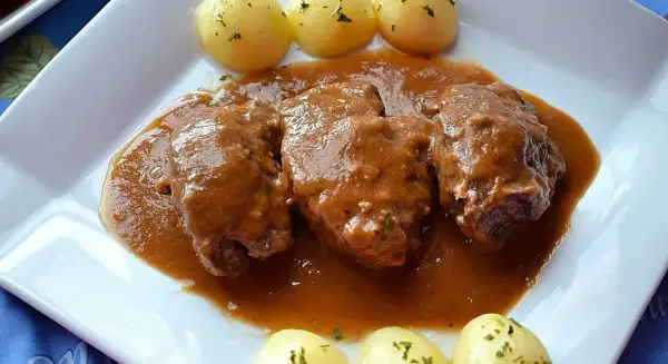 Carrilleras de ternera estofadas en salsa, acompañadas de patatas cocidas con perejil picado. Un plato casero que huele a tradición.